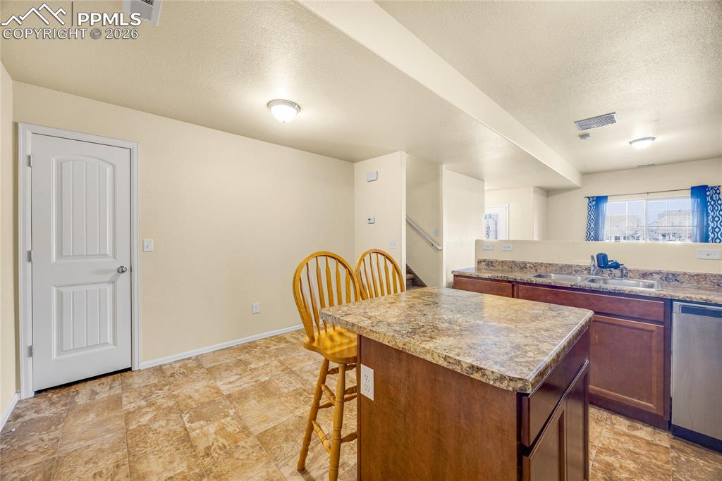 Image 11 of 32: Bright kitchen view with island workspace and durable tile flooring through