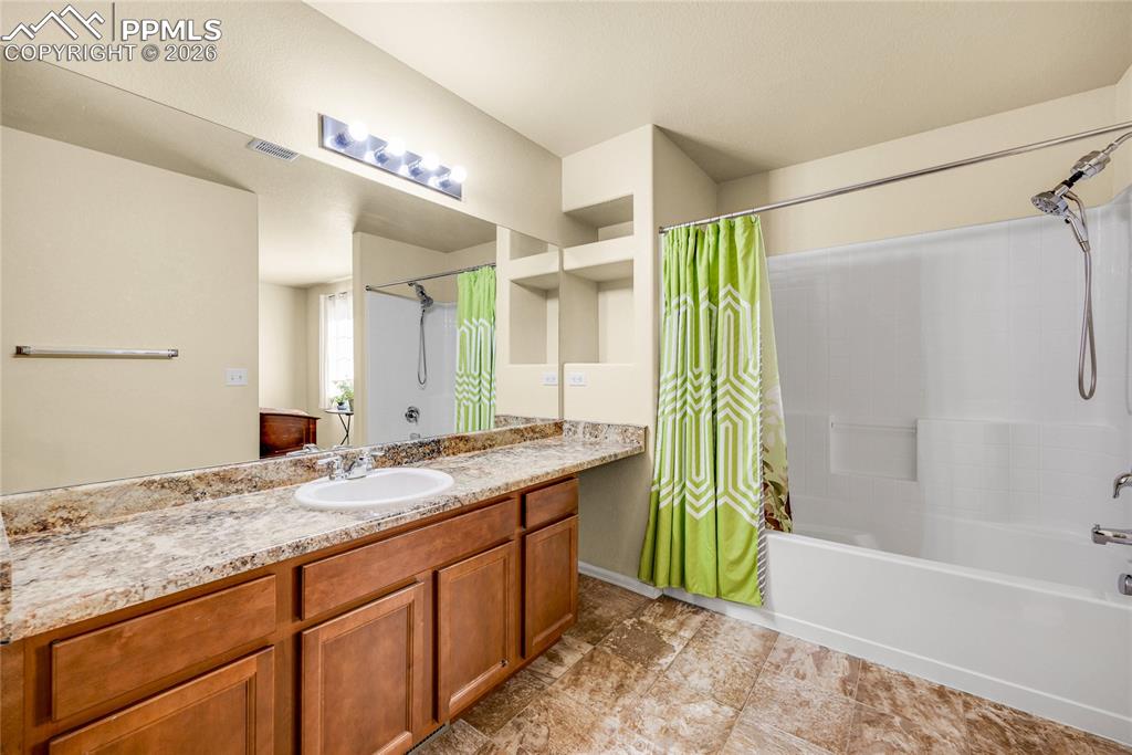 Image 19 of 32: Spacious full bath with extended vanity, tile floors, and modern lighting.
