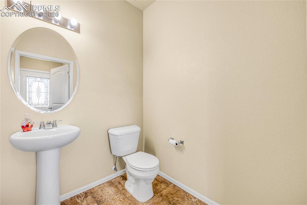 Image 7 of 32: Clean and convenient half bath with pedestal sink and updated lighting.