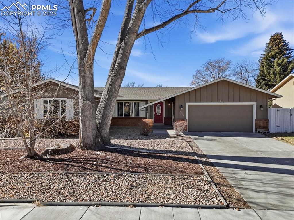 Caption: Ranch-style house with driveway, brick siding, an attached garage, and board and batten siding