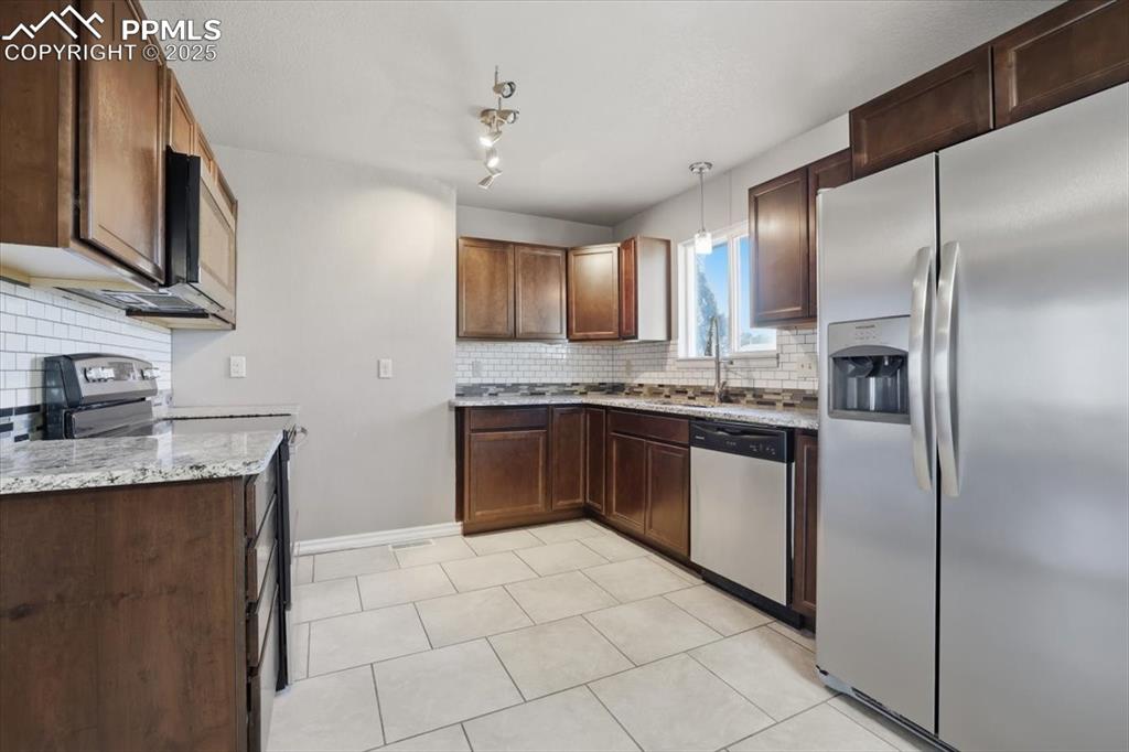 Image 11 of 48: Kitchen featuring stainless steel appliances, light stone countertops, deco