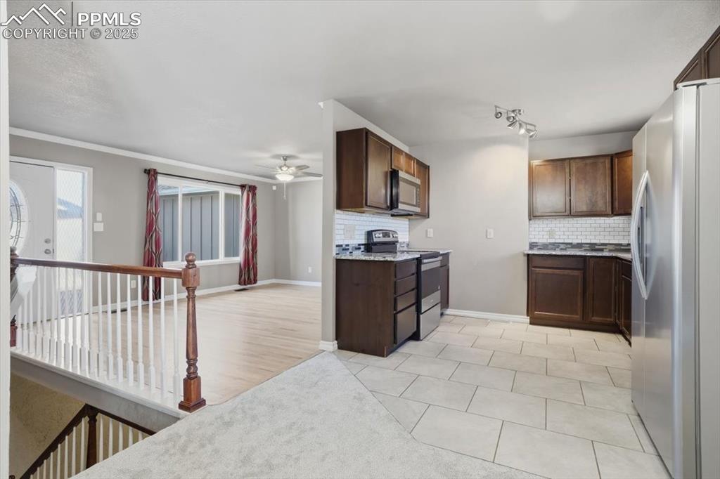 Image 15 of 48: Kitchen with stainless steel appliances, decorative backsplash, light tile 