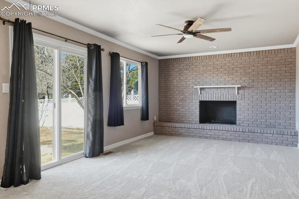 Image 17 of 48: Unfurnished living room featuring ornamental molding, a fireplace, carpet, 