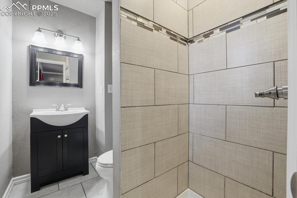 Image 21 of 48: Full bath with light tile patterned flooring, vanity, and a textured wall