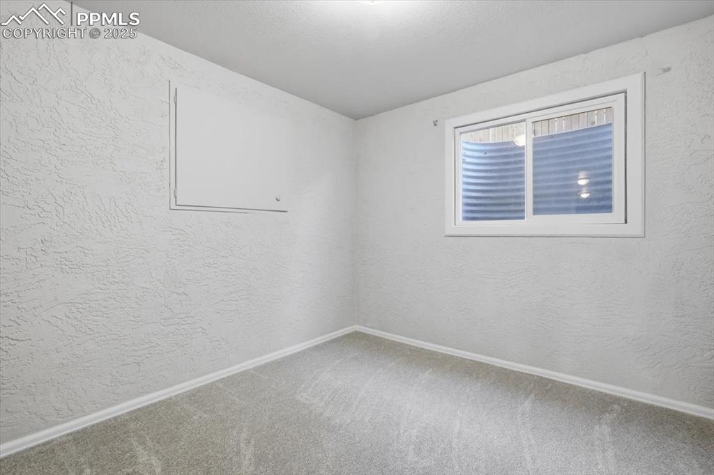 Image 35 of 48: Carpeted spare room with a textured wall and baseboards