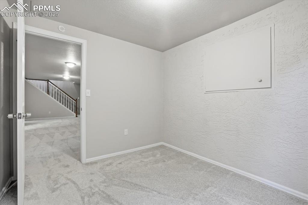 Image 36 of 48: Unfurnished room featuring light colored carpet, stairway, a textured ceili