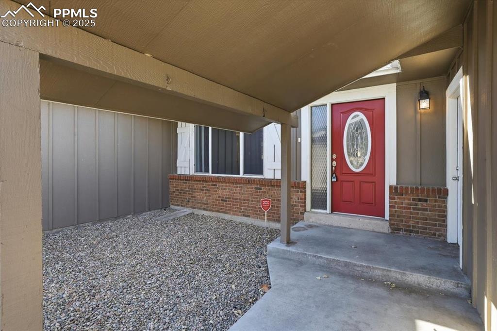 Image 44 of 48: Doorway to property featuring covered porch and brick siding