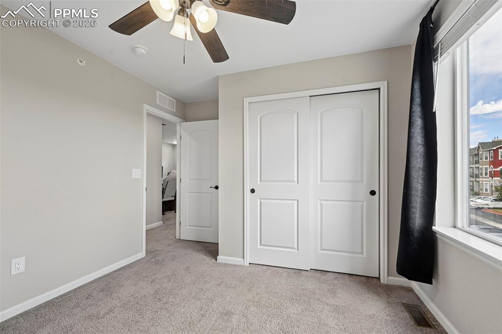 Image 18 of 42: Carpeted room with a ceiling fan, a window, and a white bi-fold closet