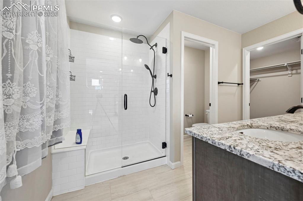 Image 19 of 42: Glass-enclosed shower with subway tile surround and built-in bench