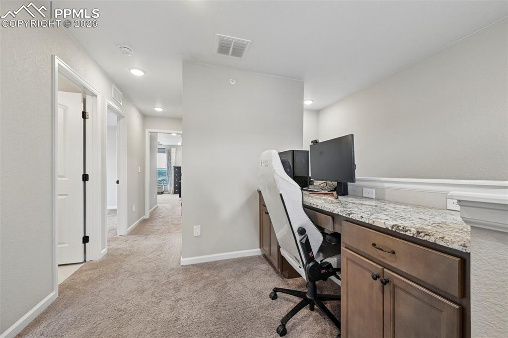 Image 23 of 42: Built-in desk featuring a stone-finish countertop and wood cabinetry