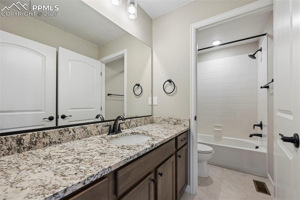 Image 24 of 42: Bathroom vanity featuring a speckled countertop, integrated sink, and dark 