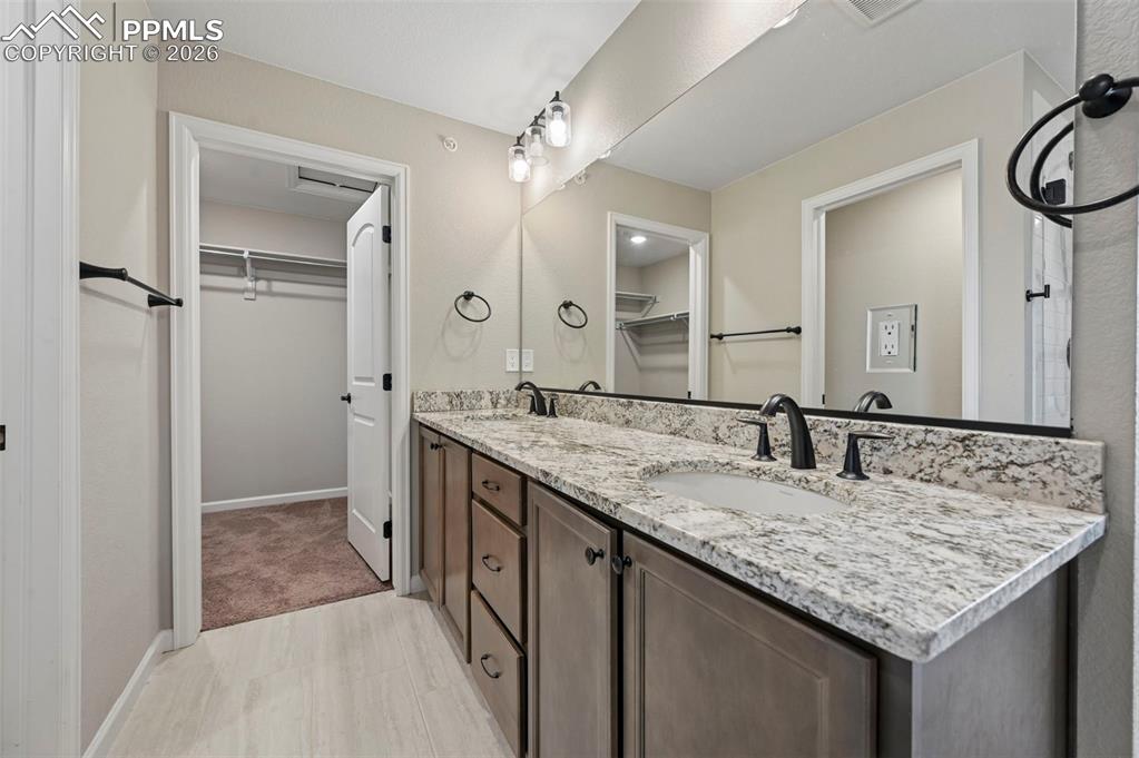 Image 25 of 42: Dual vanity featuring granite countertops, undermount sinks, and matte blac
