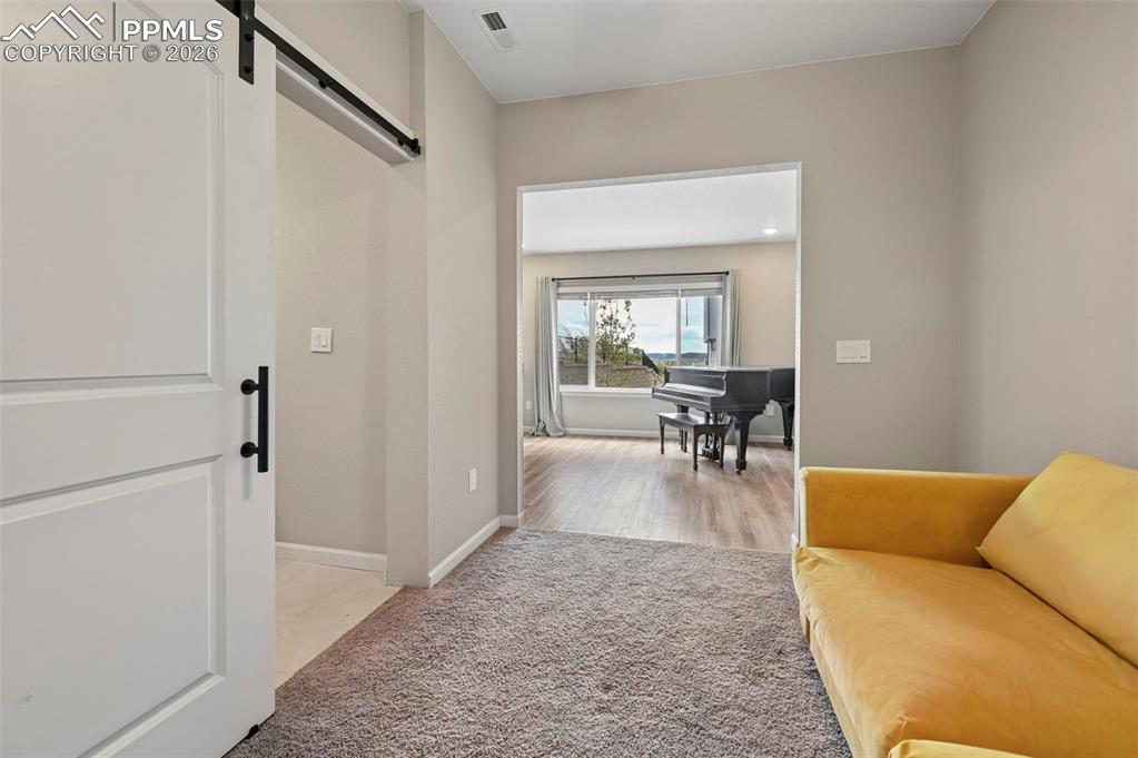 Image 27 of 42: Barn door entry with black hardware, neutral wall paint, and gray carpet