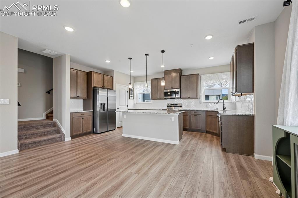 Image 6 of 42: Open-concept kitchen featuring wood-finish flooring, recessed lighting, sta