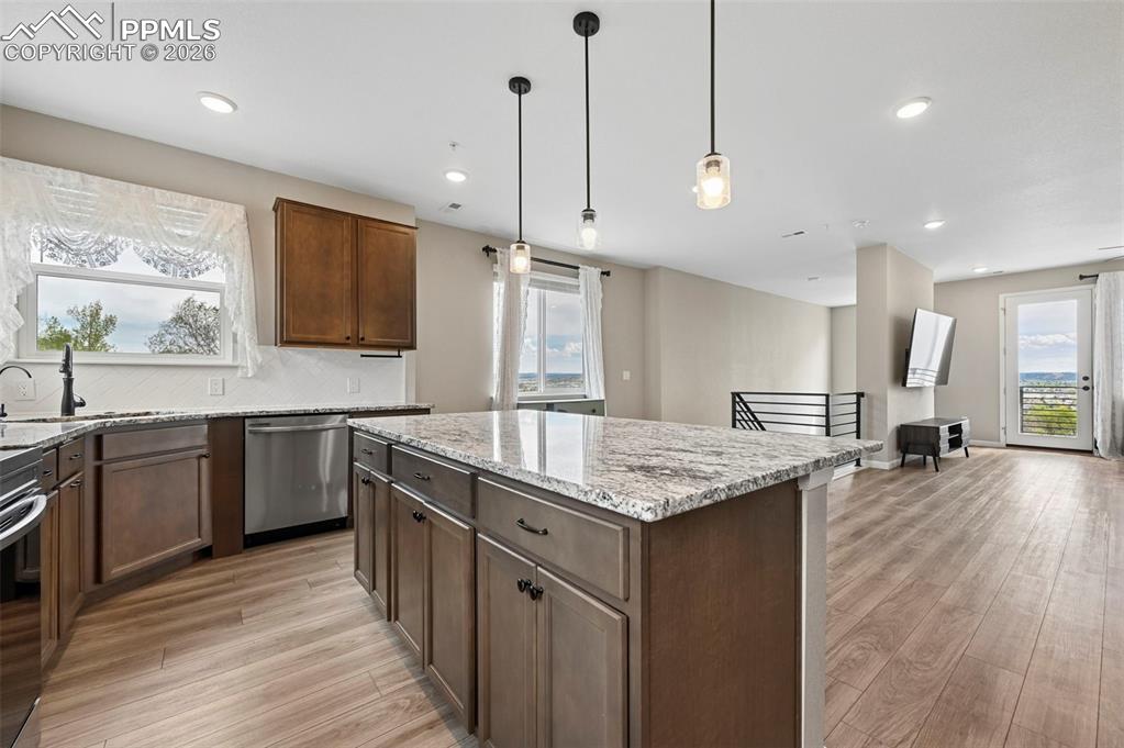 Image 7 of 42: Kitchen featuring a large island with granite countertops, wood-finish floo