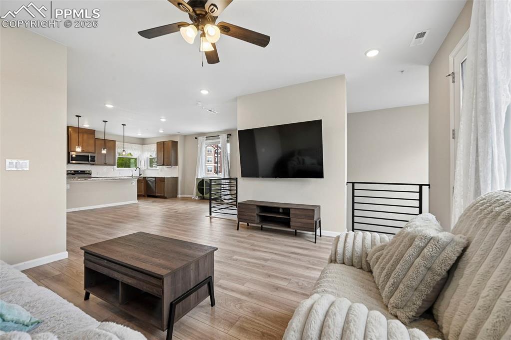 Image 9 of 42: Open-concept living area featuring wood-finish flooring, a ceiling fan with