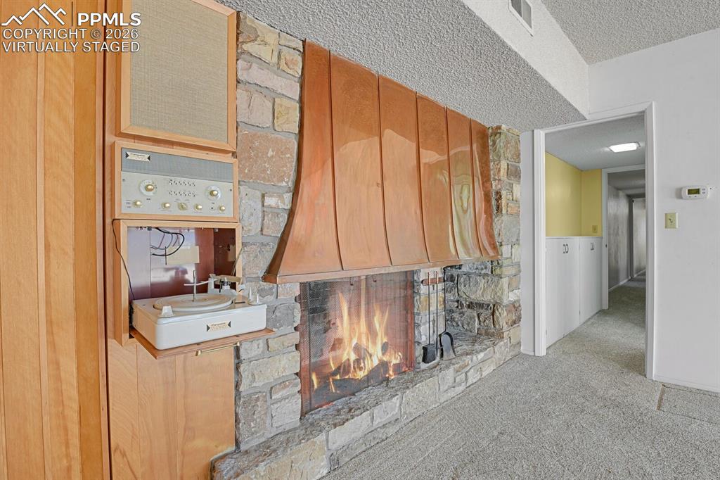 Image 29 of 49: Bsmt Rec Room w/wood burning fireplace & copper hood. *Active fire virtuall