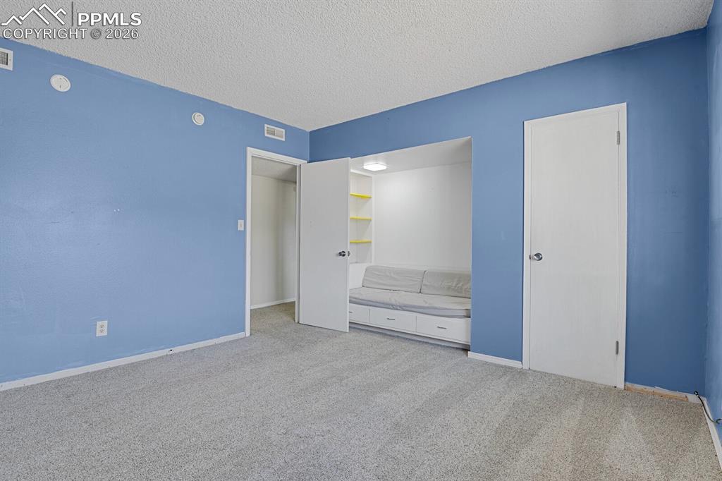 Image 33 of 49: Basement Bedroom w/built in sitting & shelves & walk-in closet