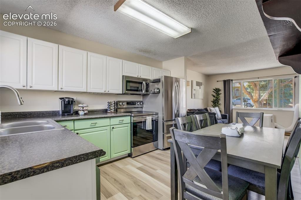 Image 11 of 50: Kitchen featuring white upper cabinetry, green lower cabinetry, and stainle