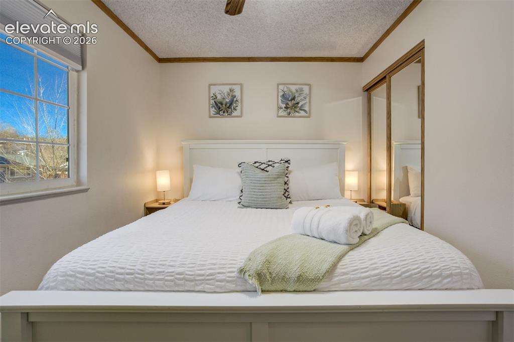 Image 14 of 50: White paneled headboard and footboard, double-pane window, wall-mounted lig