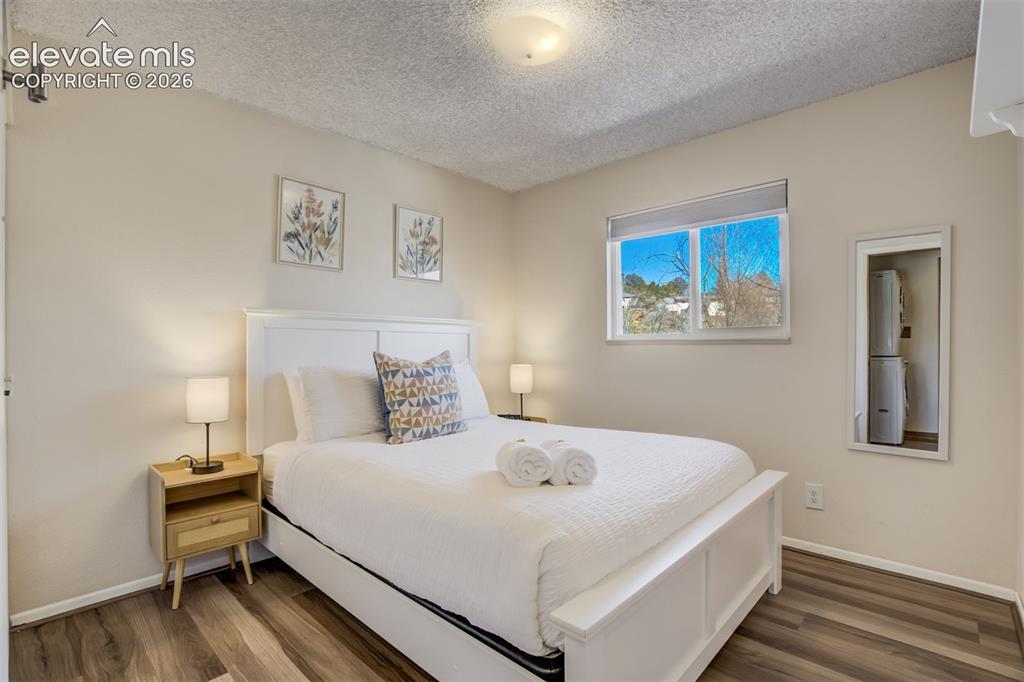 Image 16 of 50: Recessed window with roller shade, wood-finish flooring, and neutral wall p