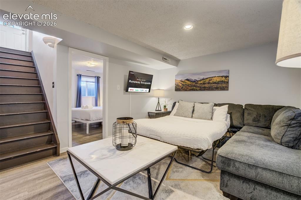Image 24 of 50: Wood-finish flooring, recessed lighting, and a wall-mounted television