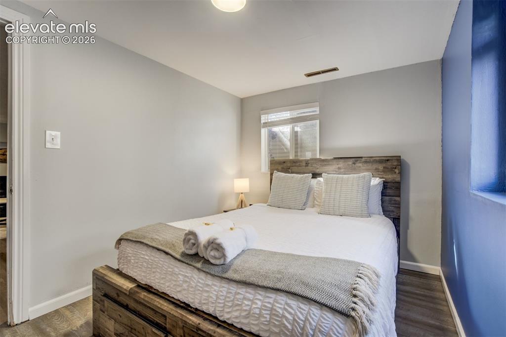 Image 32 of 50: Wood-finish flooring, a window with horizontal blinds, and a built-in light