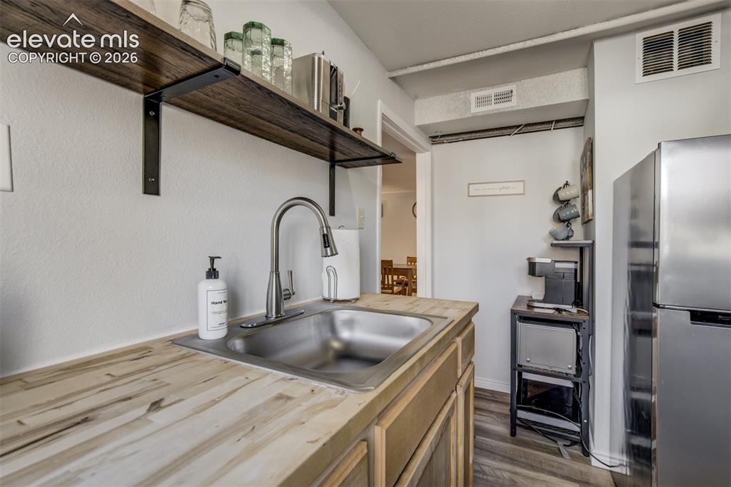 Image 36 of 50: Stainless steel sink with a gooseneck faucet, light wood-finish countertops