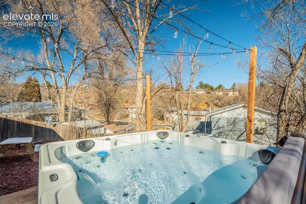 Image 43 of 50: Outdoor spa with a fitted cover, integrated seating, and a string light ins