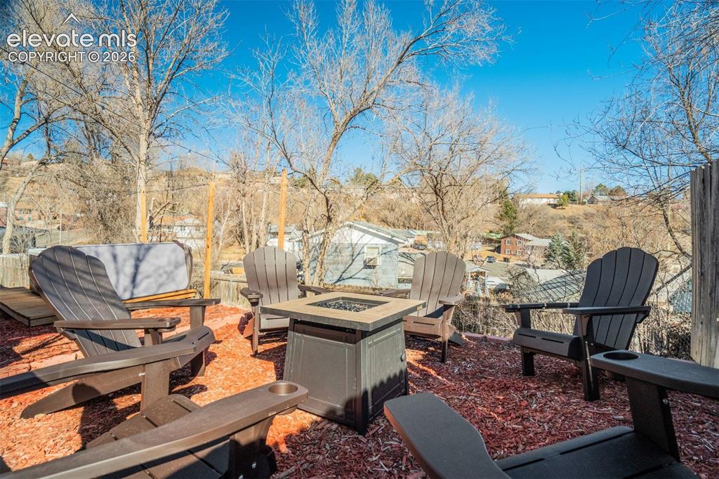 Image 44 of 50: Outdoor patio area with a built-in fire pit, multiple Adirondack-style chai