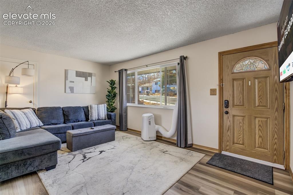 Image 5 of 50: Wood-finish flooring, textured ceiling, a multi-pane window, and a paneled 