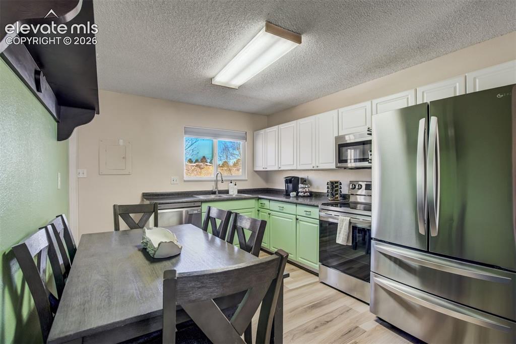 Image 8 of 50: Kitchen with dual-tone cabinetry, stainless steel appliances, dark countert