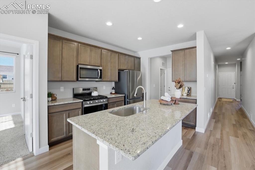 Image 10 of 34: Kitchen featuring stainless steel appliances, light stone countertops, rece