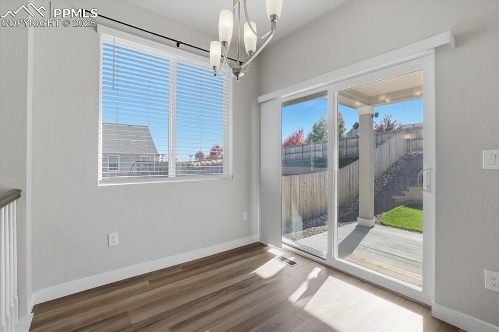 Image 12 of 34: Unfurnished dining area featuring a chandelier and wood finished floors