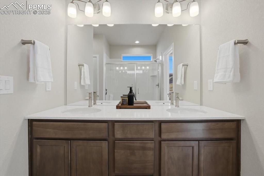 Image 17 of 34: Bathroom with double vanity, a shower stall, and a textured wall