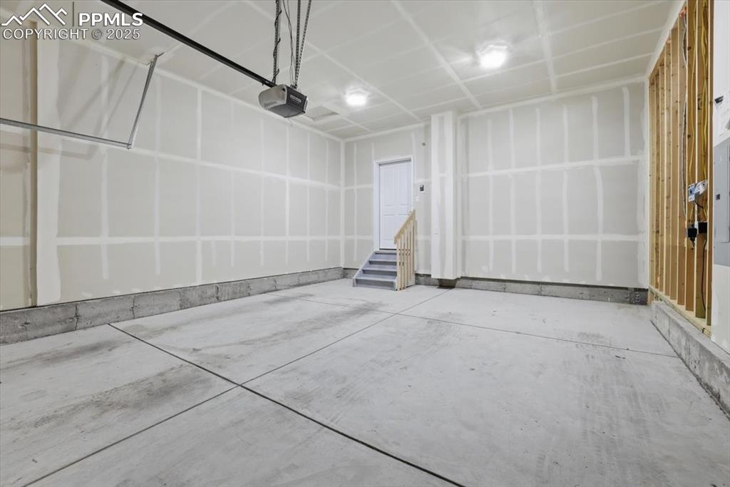 Image 28 of 34: Garage featuring a garage door opener and electric panel