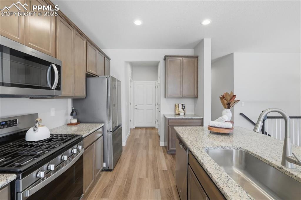 Image 3 of 34: Kitchen with appliances with stainless steel finishes, light wood-style flo