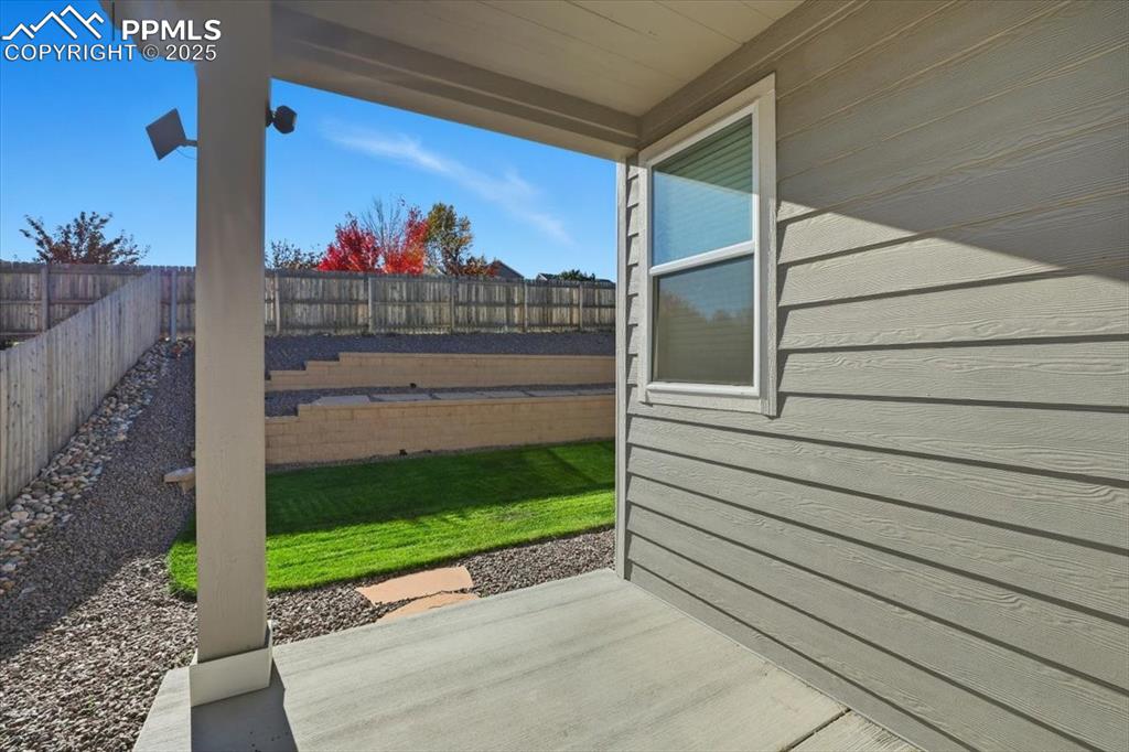 Image 32 of 34: Fenced backyard with covered patio and professional landscaping