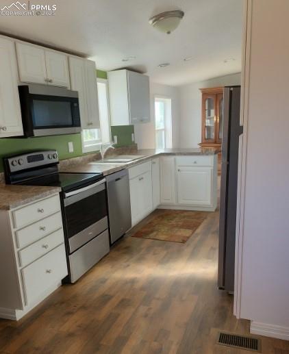 Image 2 of 9: Kitchen featuring appliances with stainless steel finishes, white cabinetry