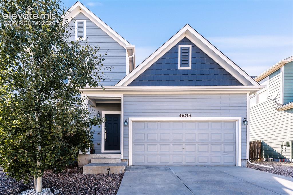 Caption: Two-story residence featuring light blue siding with dark blue shake accents, an attached two-car ga