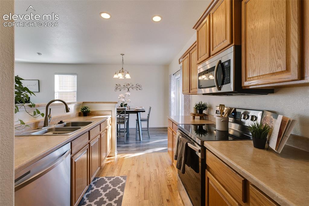 Image 16 of 36: Kitchen with wood-finish flooring, recessed lighting, wood cabinetry, stain
