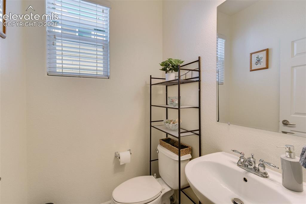 Image 18 of 36: Recessed window with blinds, wall-mounted mirror, white pedestal sink with