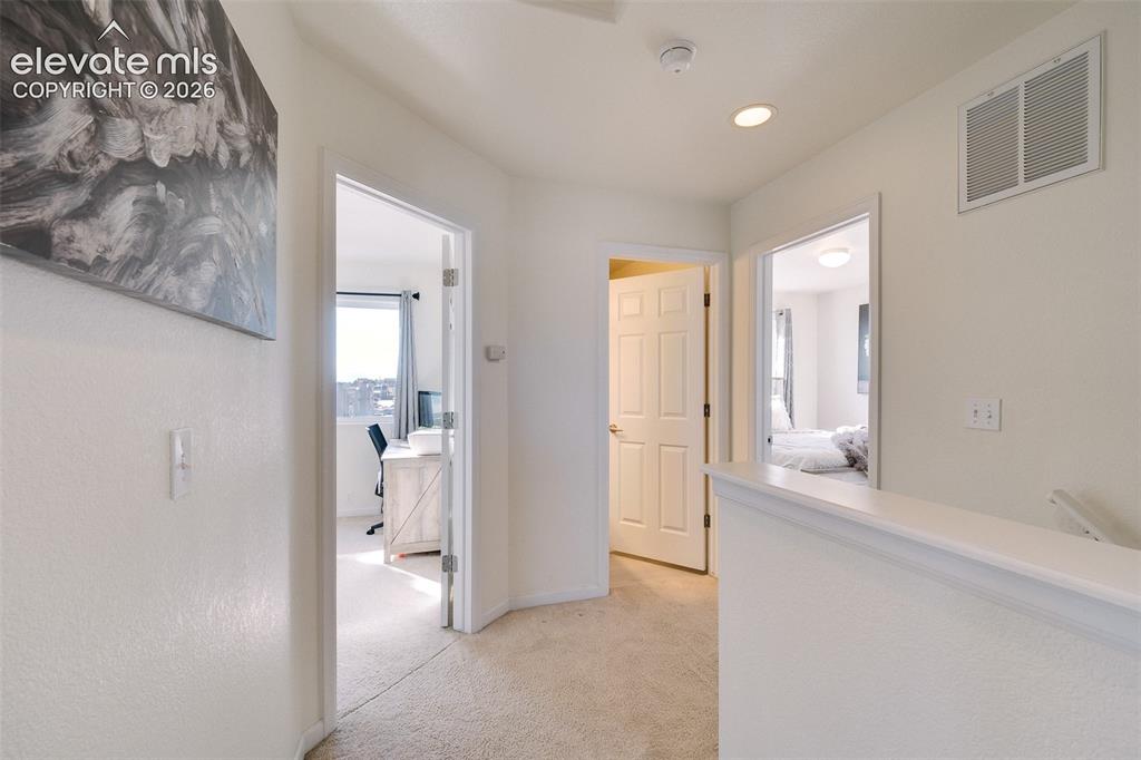Image 19 of 36: Upper-level landing with carpeted flooring, white painted walls, recessed l