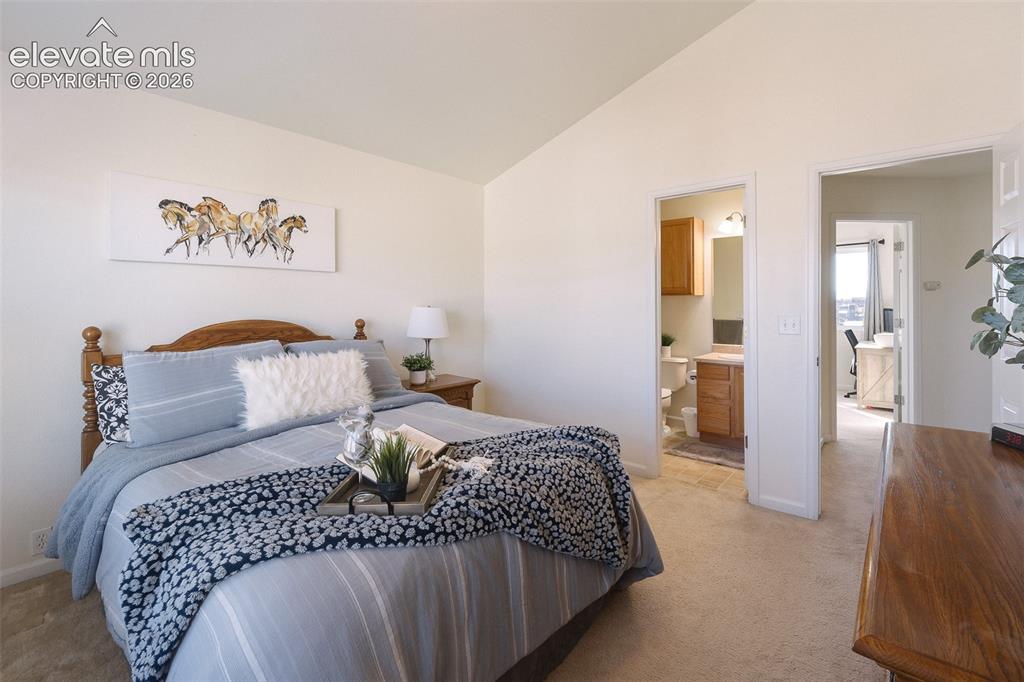 Image 20 of 36: Vaulted ceiling, neutral wall paint, carpet flooring, a built-in bathroom v