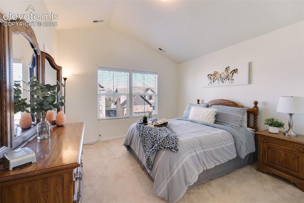 Image 21 of 36: Vaulted ceilings, neutral wall color, carpeted flooring, and a pair of wind