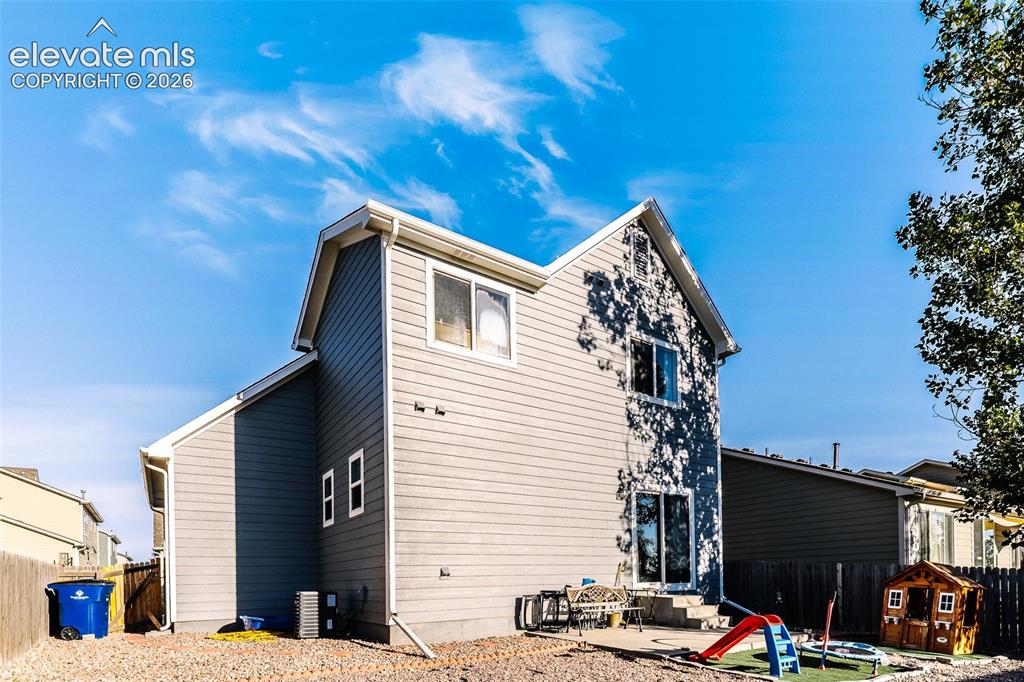 Image 33 of 36: Two-story siding exterior with multiple windows, a sliding glass door, and 