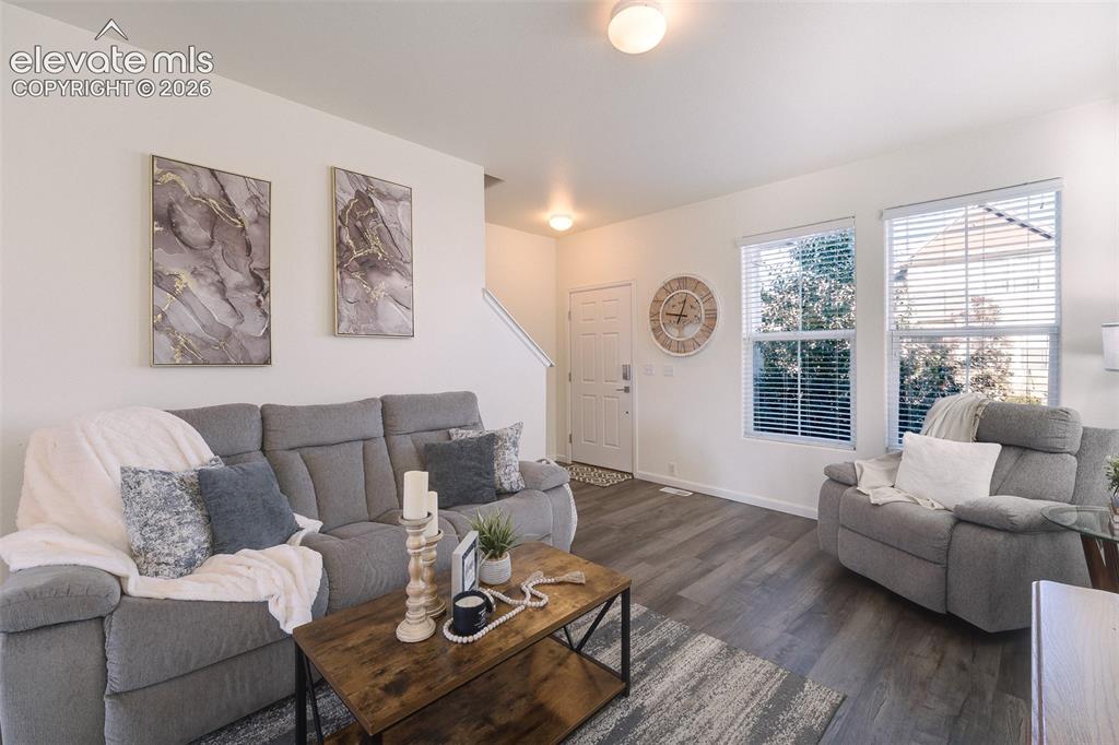 Image 7 of 36: Living area featuring wood-finish flooring, two large windows with blinds,