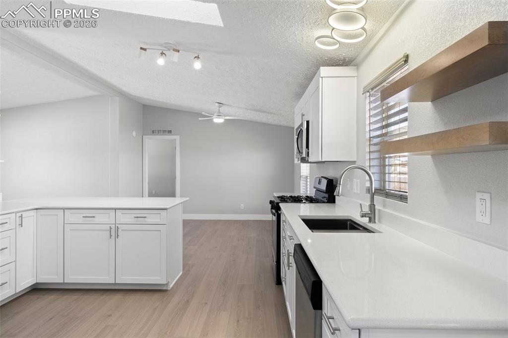 Image 24 of 50: Kitchen with white cabinetry, appliances with stainless steel finishes, and