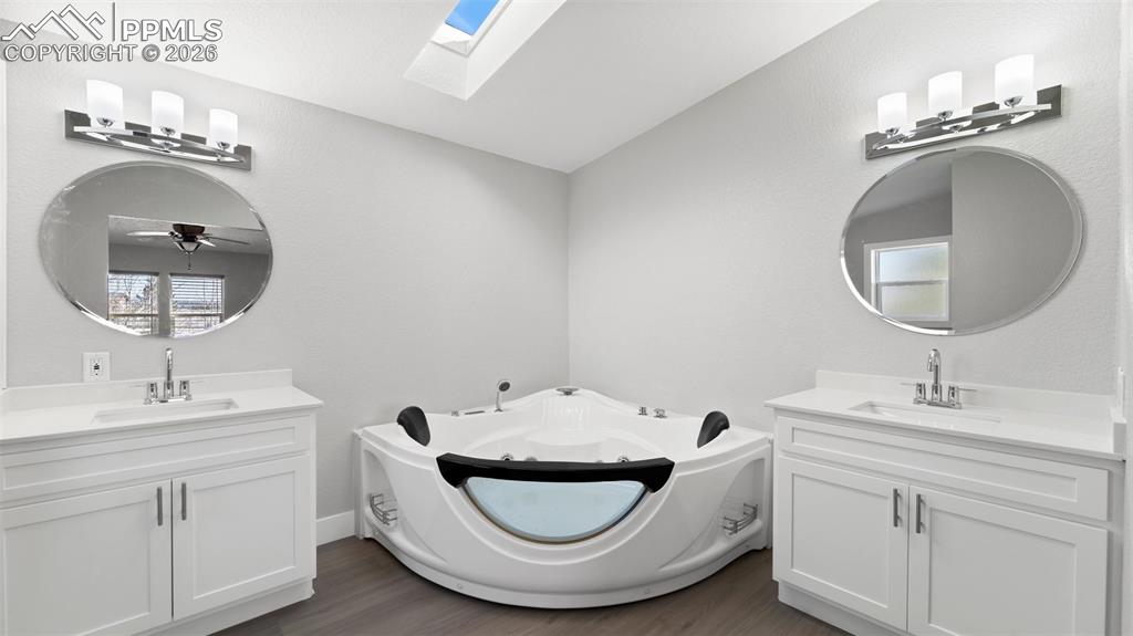 Image 28 of 50: Bathroom with vanity, a tub to relax in, and hardwood / wood-style floors