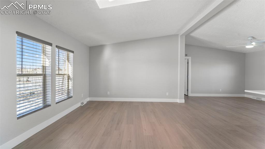 Image 38 of 50: Unfurnished room featuring wood-type flooring, ceiling fan, and a textured 